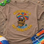 Brown t-shirt with a cartoon character and text on a sandy background